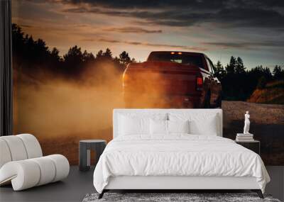 Pickup truck in motion on a country road with clouds of dust. An SUV is driving fast during sunset on a rural gravel road with a lot of dust. fast moving car Wall mural