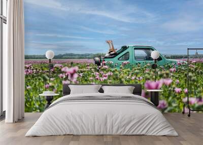 Happy women in cabriolet in poppy seed field Wall mural