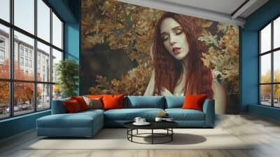 Portrait of a beautiful young sensual woman with very long red hair in autumn oak leaves. Colors of autumn. Wall mural