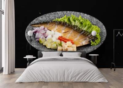 Fresh mackerel fillet served with chopped vegetables on a stone plate, isolated on a black background. Wall mural