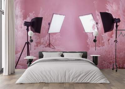 A photo studio with a pink backdrop and two lights with softboxes set up in front of white fluffy plants. Wall mural