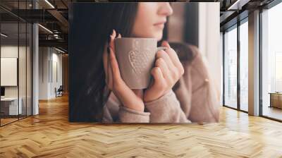 Brunette woman 20-24 year old holding ceramic cup of tea closeup. Looking at window. Good morning. Selective focus. 20s. Wall mural