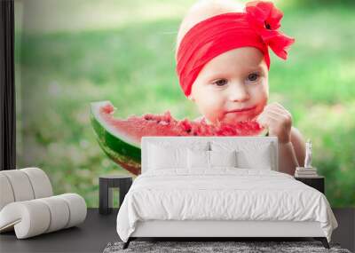 Cute baby girl eating watermelon outdoors. Summer time. Green nature background. Childhood. Wall mural