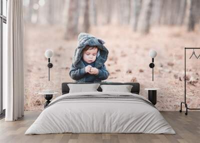 Funny baby wearinganimal suit with hood in forest. Winter season. Childhood. Wall mural