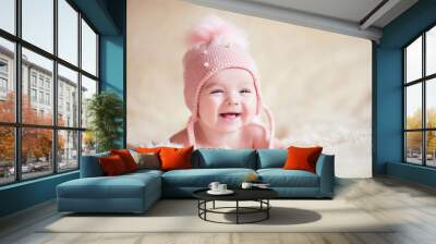 Happy baby girl wearing stylish knitted hat lying in bed close up. Childhood. Wall mural