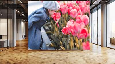 Stylish girl 1-2 year old smelling flowers in park closeup. Spring season. Childhood. Wall mural