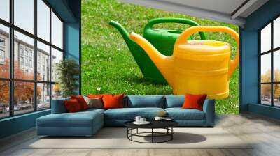 two watering cans on a green fie Wall mural