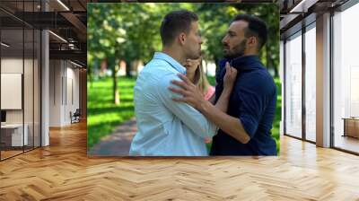 Aggressive men fighting outdoors, scared girlfriend trying calm down, conflict Wall mural