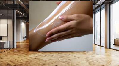 Female hands applying moisturizing body lotion on leg after depilation, hygiene Wall mural