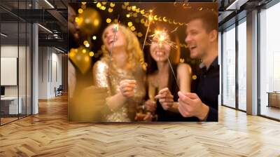 Four joyful colleagues holding burning sparklers and champagne glasses, party Wall mural