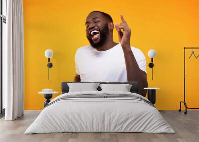 Happy relaxed black man dancing against yellow background, having fun on party Wall mural