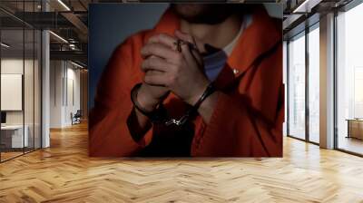 Imprisoned male in handcuffs holding cross and praying, feeling guilty, regret Wall mural