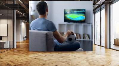 Man watching game on tv at home supporting one of soccer team, match result Wall mural