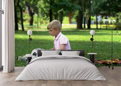 Sad boy sitting in park with football, lack of friends, victim of bullying Wall mural