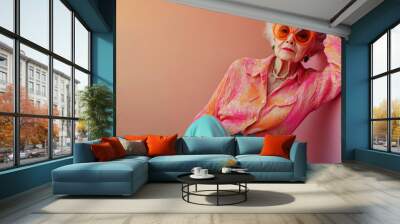 Relaxed vibe Beautiful old woman grandmother in stylish sportive trousers posing on vintage rollers over pink studio background Concept of age fashion lifestyle emotions facial express Wall mural