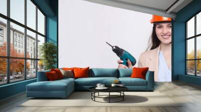 Girl engineer in an orange construction helmet with a screwdriver and a hammer on a white background. Wall mural