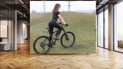 Girl on a mountain bike on offroad, beautiful portrait of a cyclist in rainy weather, Fitness girl rides a modern carbon fiber mountain bike in sportswear. Close-up portrait of a girl in red bandana. Wall mural