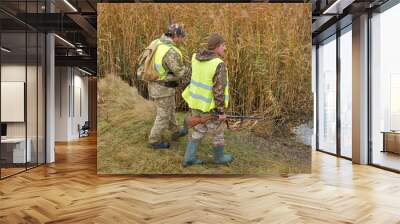 Hunter with a gun and a dog go on the first snow in the steppe, Hunting pheasant in a reflective vest	 Wall mural