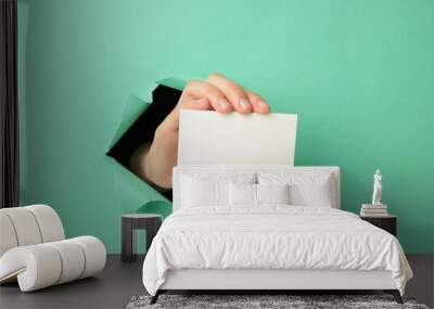 Female hand with gift box punching through the pink paper Wall mural