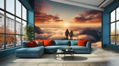 Couple of man and woman hikers on top of a mountain in winter at sunset or sunrise, together enjoying their climbing success and the breathtaking view, looking towards the horizon Wall mural