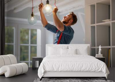 A cheerful electrician is attentively installing or repairing a light bulb in a residential setting Wall mural