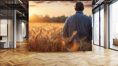 A farmer is standing in a field of wheat Wall mural