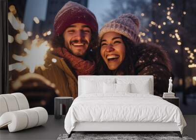 A happy couple in winter attire, holding a sparkler and sharing a joyful moment together at night. Wall mural