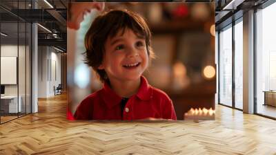 A smiling boy is looking at a birthday cake with lit candles. Wall mural