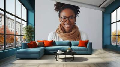 a smiling person is wearing round eyeglasses and a scarf, giving off a relaxed and stylish vibe against a gray background. Wall mural