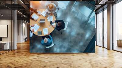 Aerial view of a professional meeting with four individuals around a round table Wall mural