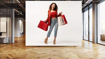 Beautiful attractive smiling woman holding shopping bags posing on light grey background Wall mural