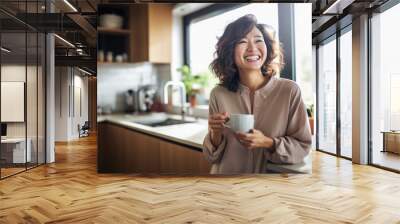 Beautiful woman smiling with a cup of coffee in the kitchen of her home Wall mural