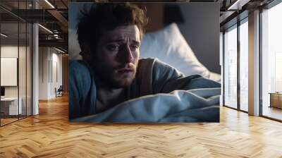 Depressed man lying in bed can't sleep late at morning with insomnia. Wall mural