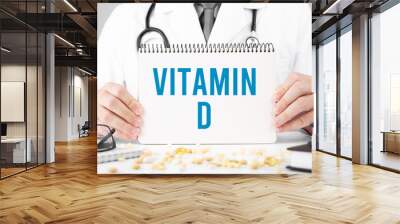 Doctor in a dressing gown holds a notepad with text Vitamin D, Medical concept Wall mural