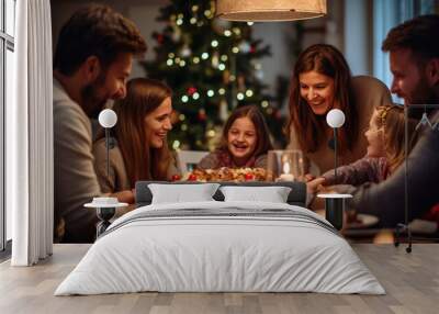 Family enjoying a warm, festive Christmas dinner together, with children smiling, candles glowing, and a decorated Christmas tree in the background. Wall mural