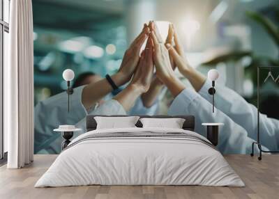 Group of medical professionals in scrubs and white coats, putting their hands together in a unified gesture Wall mural