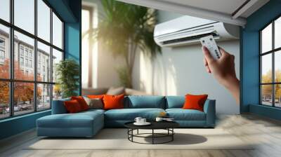 Hand holding remote control aimed at the air conditioner. Woman turning on air conditioner with remote control. Wall mural