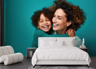 Happy mother and daughter smiling and hugging against the blue background. Wall mural