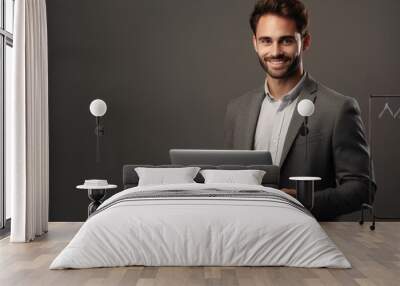 Happy young man working on a laptop against grey background Wall mural