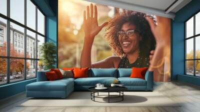 Joyful woman with glasses, smiling widely and giving a high-five, indicating a positive interaction or celebration Wall mural