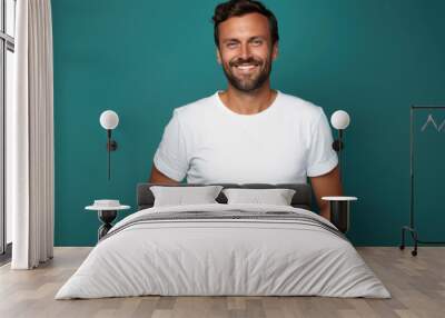 Man standing in front of camera in white T-shirt , isolated on blue background Wall mural