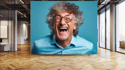 Middle-aged man laughs against a blue background. Wall mural