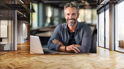 Middle aged man working on a laptop in his modern office Wall mural