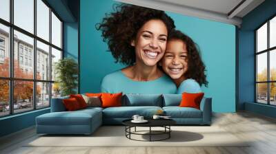 Mother and daughter hugging and laughing against a blue background. Created with Generative AI technology. Wall mural