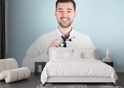 Professional male actor ready for shooting film, holds movie clapper, isolated on blue background. Wall mural