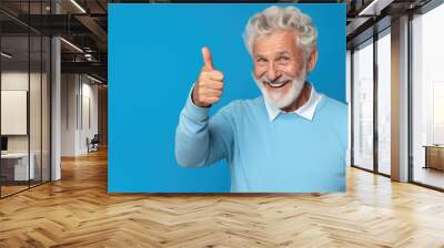 Senior man standing over isolated blue background doing happy thumbs up gesture with hand. Wall mural