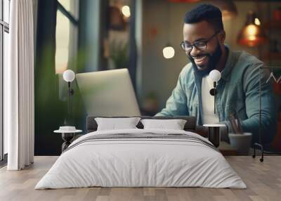 Smiling man working on a laptop in his office Wall mural