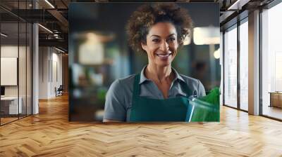 Smiling woman in a cleaning service uniform with colleagues in the background, indicating a professional cleaning team at work. Wall mural