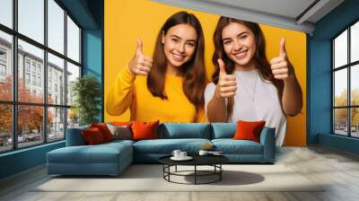 Two Cheerful happy young girls students make fingers thumbs up smile isolated on yellow color background.Created with Generative AI technology. Wall mural