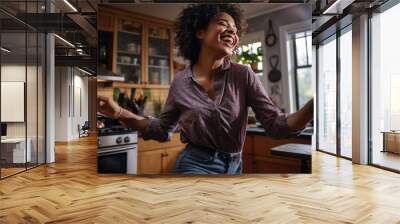 Woman dances in the kitchen while cooking dinner at home Wall mural